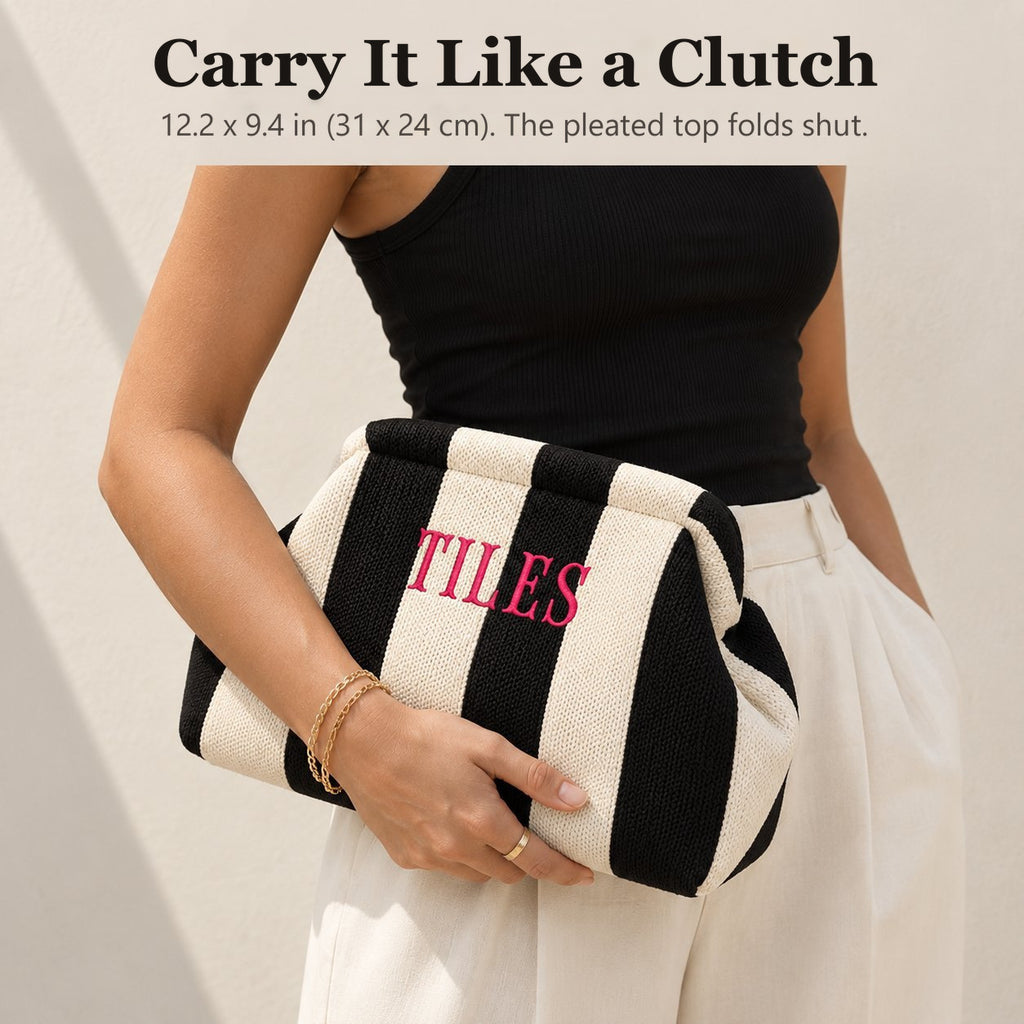 Woman carrying a black and ivory striped mahjong tile bag as a clutch, embroidered "Tiles" in hot pink