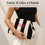 Woman carrying a black and ivory striped mahjong tile bag as a clutch, embroidered "Tiles" in hot pink