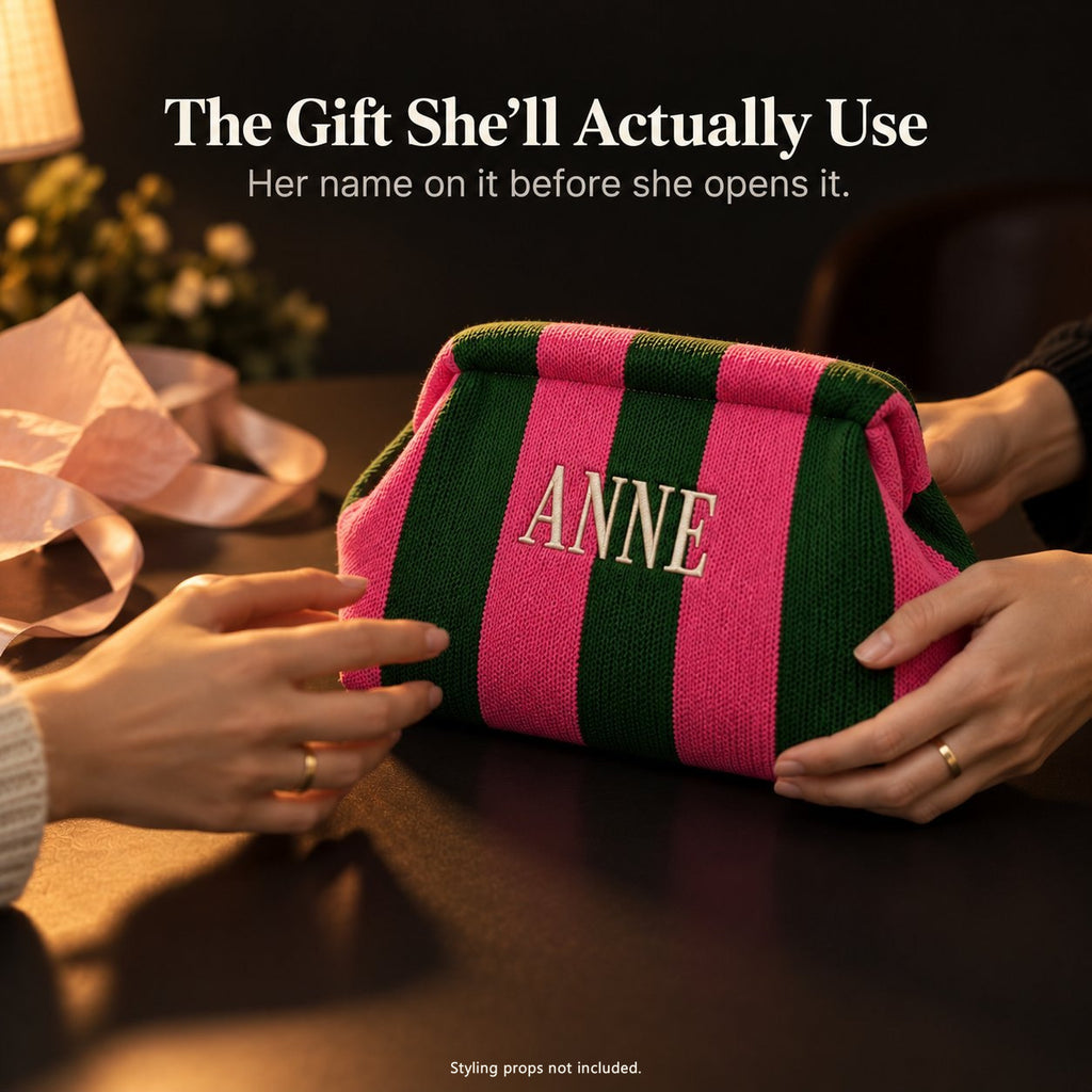 Hands passing a green and hot pink mahjong tile bag embroidered "Anne", with pink tissue paper and ribbon