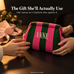 Hands passing a green and hot pink mahjong tile bag embroidered "Anne", with pink tissue paper and ribbon
