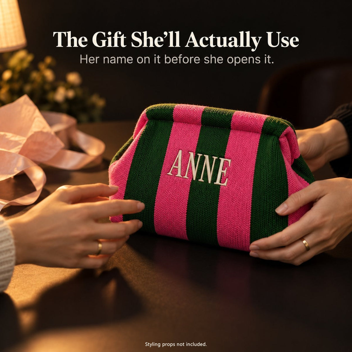Hands passing a green and hot pink mahjong tile bag embroidered "Anne", with pink tissue paper and ribbon